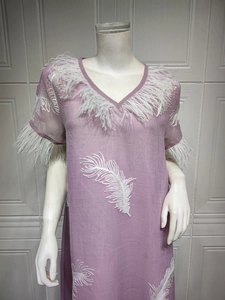 Detail of V-neck dress with white feather fringe and intricate embroidery on mauve fabric
