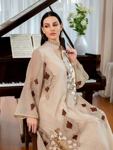 Elegantes beige Kaftan-Kleid mit brauner Stickerei und Goldpailletten am Klavier.
