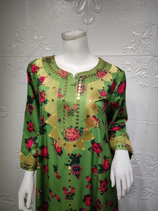 Close-up of green floral dress featuring golden embroidery and sequins at the neckline