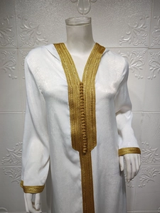 Detail of white satin kaftan with intricate gold braided embroidery and stand collar