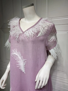 Close-up of V-neckline with delicate white feather trim and embroidery on purple dress