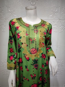 Detail of green kaftan dress featuring silk texture and gold sequin embroidery on neckline