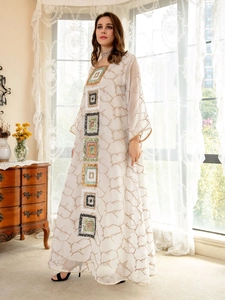 Detail of the white kaftan dress featuring colorful sequin embroidery and abstract patterns