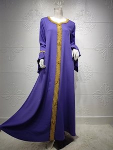 Detailed close-up of golden fringe and beadwork on the neck and cuffs of the purple abaya