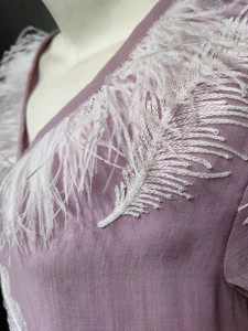 Detail of V-neck mauve dress featuring white feather embroidery and tassel fringe trim