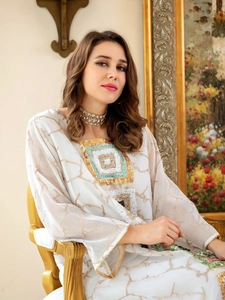 Detail of white sequin kaftan dress with colorful embroidery and wide sleeves
