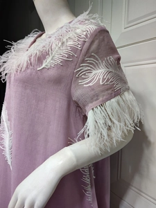 Detail of lavender dress featuring white feather trim and intricate wing embroidery