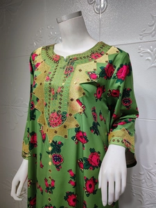 Detail of green satin dress with red floral patterns and intricate gold embroidery
