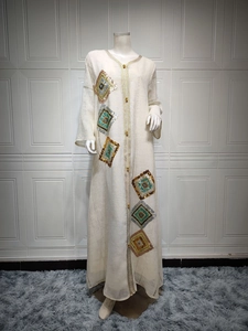 Détail de la broderie à paillettes et bordure dorée sur cette robe abaya crème