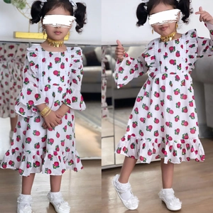 Détail d'une robe fleurie pour fille avec motifs de roses rouges et volants aux manches