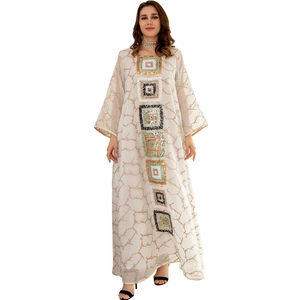 Detail of sequin embroidery and intricate branch pattern on a long-sleeved beige dress