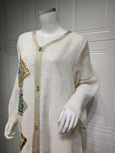 Détail du caftan à col en V avec bordure dorée et broderies de paillettes colorées