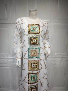 Detail of white long sleeve kaftan dress with intricate gold embroidery and large sequins