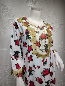 Detail showing the intricate gold embroidery and green sequins on white floral dress