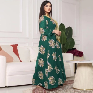 Détail d'une robe caftan vert foncé avec broderie florale dorée et détails de paillettes