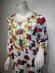 Close-up of golden sequins and floral embroidery on a white long sleeve kaftan dress