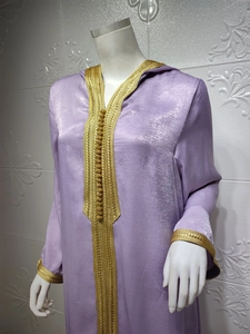Close-up of golden embroidery and sphere buttons on champagne violet hooded kaftan