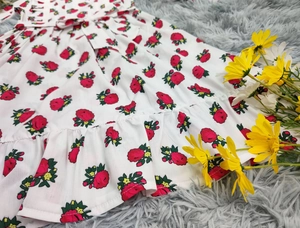 Détail d'une robe fleurie blanche pour fille avec ourlet à volants et lien de taille
