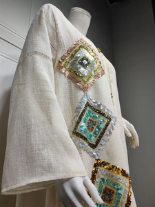 Détail de la broderie à paillettes et des découpes ajourées sur la robe caftan beige