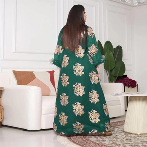 Détail d'un caftan vert foncé avec broderie dorée et poignets en plumes d'autruche