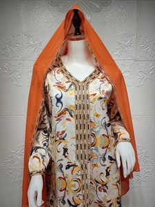 Détail d'une abaya ethnique aux motifs colorés avec broderies dorées et hijab orange vif