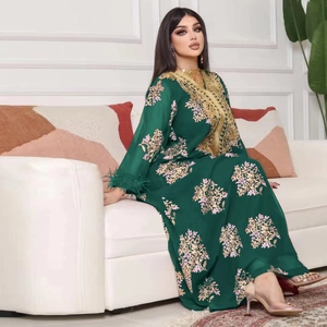 Détail du caftan vert foncé avec broderies dorées et plumes aux poignets de la robe