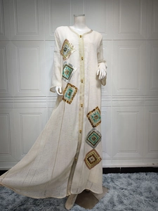 Détails de broderie de paillettes et bordure dorée sur cette robe caftan beige