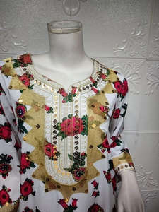 Detail view of golden sequin embroidery and red floral prints on white V-neck boho dress