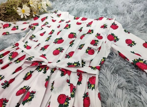 Détail de la robe à fleurs avec col à volants et ceinture nœud sur tapis en peluche