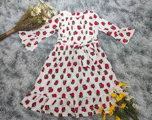 Détail de la robe fleurie pour bébé avec motif de roses rouges et manches évasées