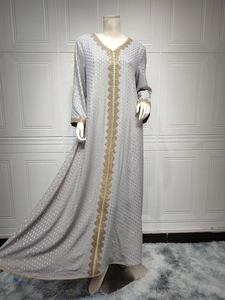 Detail eines grauen Abaya-Kleides mit Goldfolien-Punkten und geometrischer Stickerei