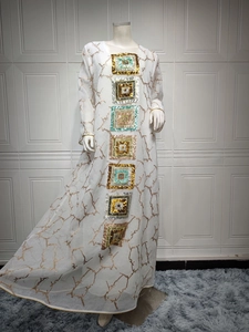 Close-up of golden branch patterns and colorful square sequins on a white dress