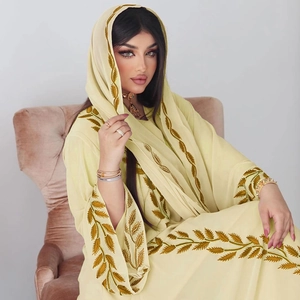 Detail of elegant light yellow Kaftan dress and matching scarf with gold leaf embroidery