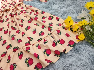 Détail de l'imprimé floral rose rouge et du nœud à la taille de cette robe pêche pour fille
