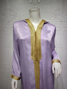 Detail of gold embroidery and decorative buttons on a lilac velvet hooded kaftan dress