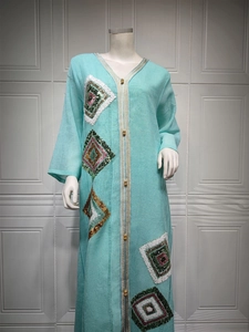 Détail de robe caftan bleu clair avec bordure dorée et broderie de paillettes