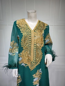 Détail de la robe vert foncé montrant la broderie dorée et les poignets en plumes d'autruche