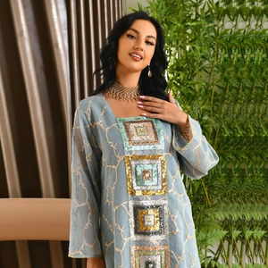 Detail of light blue kaftan with gold branch embroidery and sequin chest patches