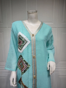 Détail de robe caftan bleu clair avec col en V et broderie de paillettes en losange