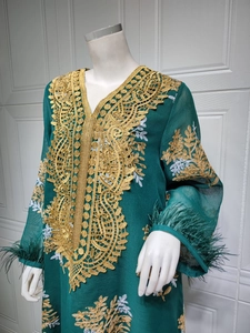 Détail d'un caftan vert avec broderie dorée, dentelle et poignets en plumes d'autruche