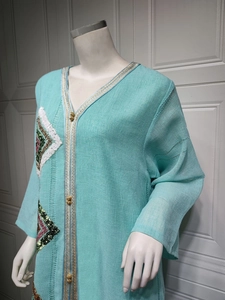 Détail d'une robe caftan vert menthe avec bordure dorée et broderies de paillettes
