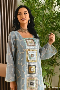 Close-up of golden sequin embroidery and branch pattern on blue chiffon kaftan dress