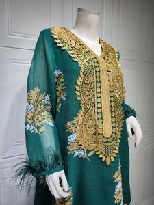 Détail de robe caftan vert foncé avec broderie dorée et finitions de manches en plumes