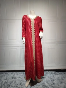 Detail eines roten Kaftans mit Goldfolien-Punkten und goldener Stickereiverzierung