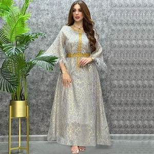 Detailreiche Bestickung am grauen Kleid mit goldenen Sechseckmustern und Federbesatz