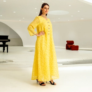 Detail of yellow kaftan with geometric embroidery and floral rhinestone buttons