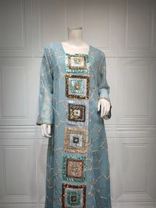 Detail of light blue kaftan dress featuring branch embroidery and sequin embellishments