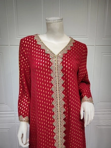 Detailaufnahme der grünen und rosa Spitzenborte am dunkelroten Jalabiya-Kleid