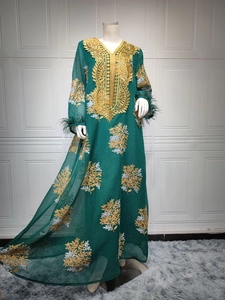 Détail de la robe verte avec broderie dorée et garniture en plumes sur les manches