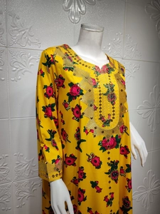 Detail of yellow floral kaftan with golden embroidery and sequins on neckline and cuffs